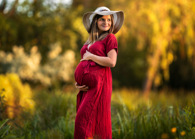 Portrait de femme enceinte en robe rouge lors d'une séance photo lifestyle maternité à Metz