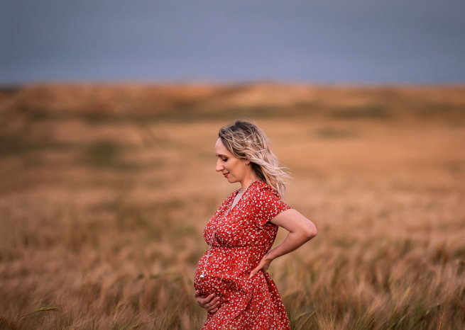 Une future maman en robe rouge pendant une séance photo maternité à Fléville-devant-Nancy