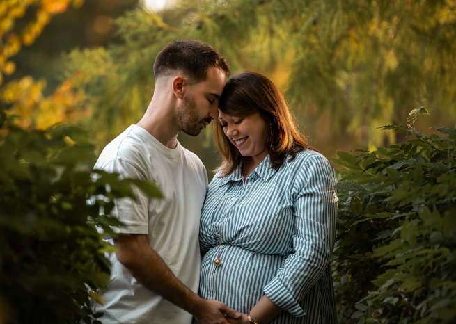 Couple de futurs parents dans un parc verdoyant près de Nancy pendant leur séance photo de maternité.