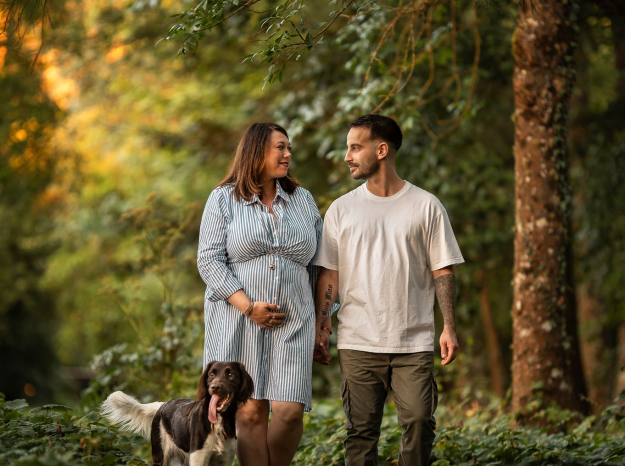 Couple attendant un bébé marchant avec leur chien de chasse sur un chemin forestier, séance lifestyle à Nancy.