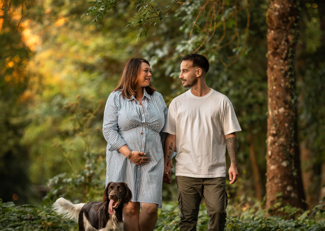Couple attendant un bébé marchant avec leur chien de chasse sur un chemin forestier, séance lifestyle à Nancy.