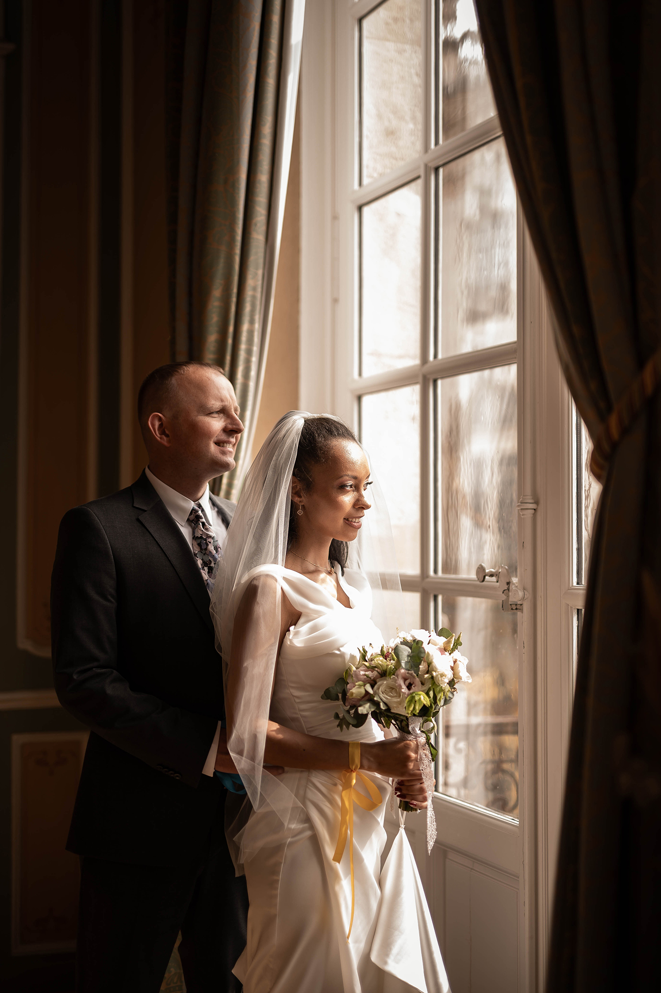 Mariés contemplant la Place Stanislas depuis une fenêtre de l'Hôtel de la Reine à Nancy, photographie de mariage élégante