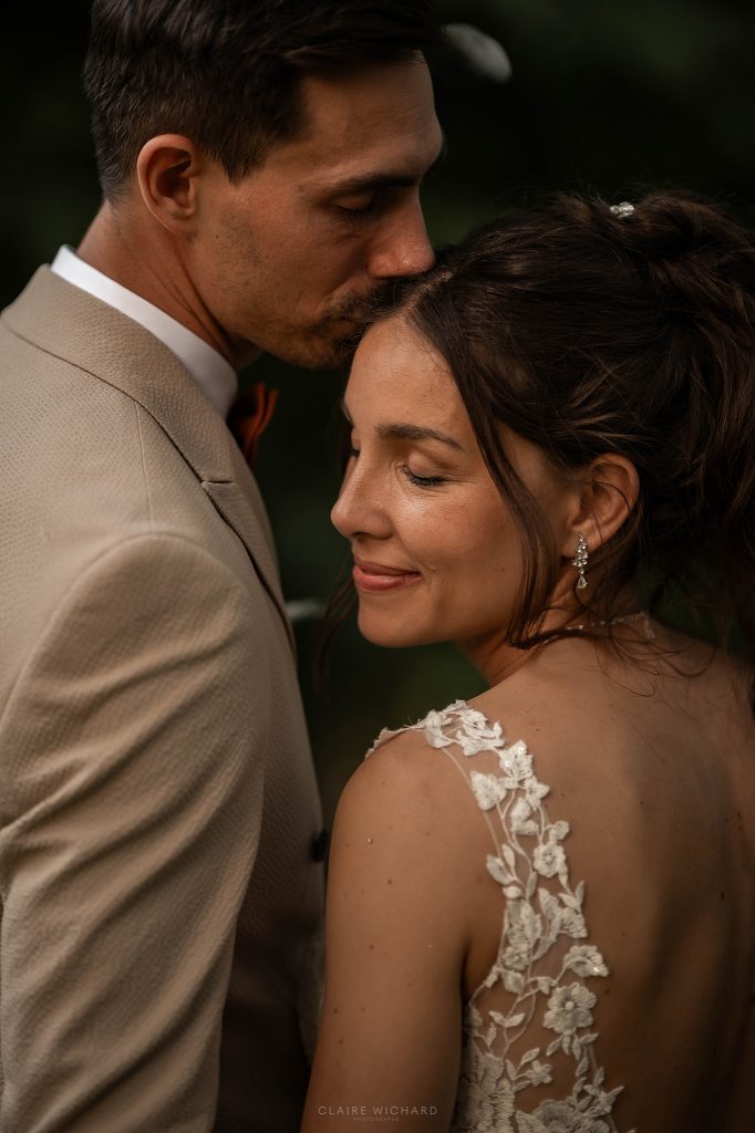 Moment de tendresse au Château Ferme d'Aboncourt : le marié embrasse le front de sa femme lors de leur mariage