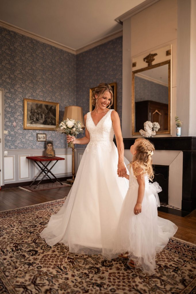 La mariée en robe de dentelle tenant la main de sa fille dans une chambre historique du Château d'Autigny-la-Tour.
