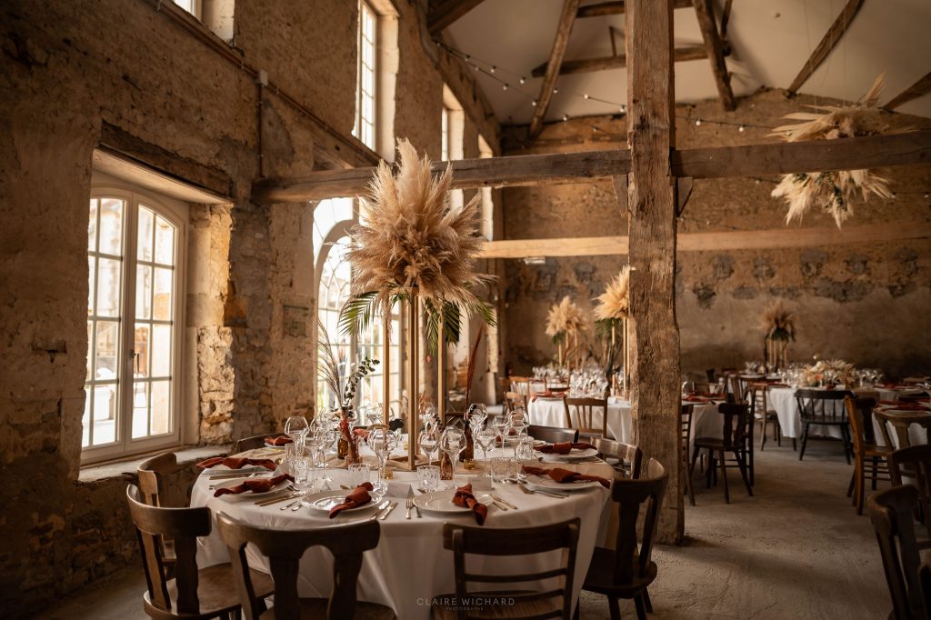 Décoration de salle de mariage avec centres de table en pampa et poutres apparentes au Château Ferme d'Aboncourt, Meurthe-et-Moselle.