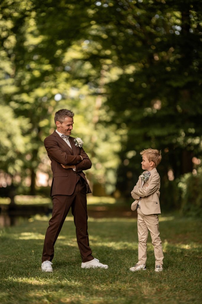 Moment de complicité entre le marié en costume marron et son fils dans le parc du Château d'Autigny-la-Tour