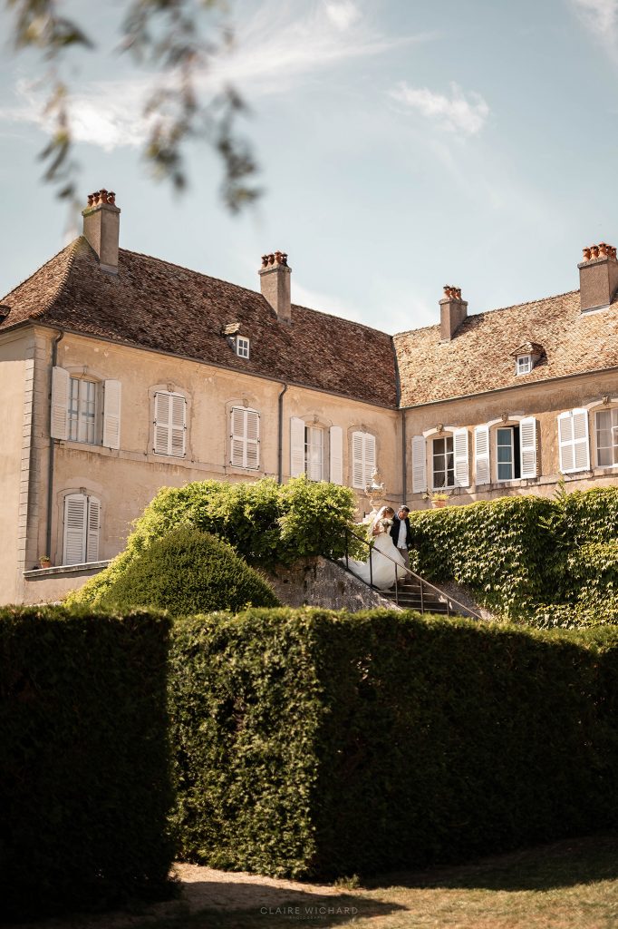 La mariée et son grand père descendant l'escalier fleuri du Château d'Autigny-la-Tour lors d'une réception de mariage en Lorraine.