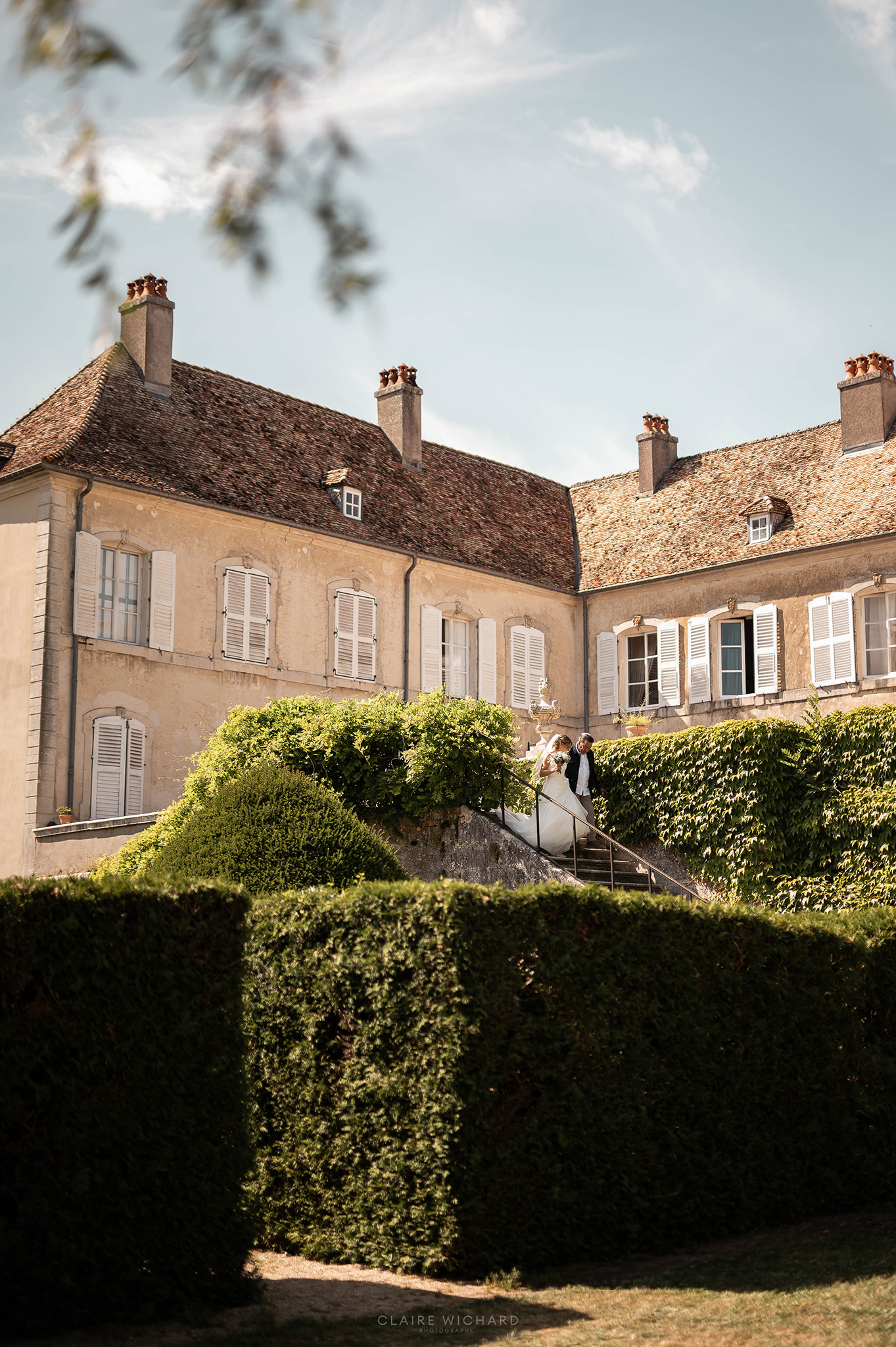 La mariée et son grand père descendant l'escalier fleuri du Château d'Autigny-la-Tour lors d'une réception de mariage en Lorraine.