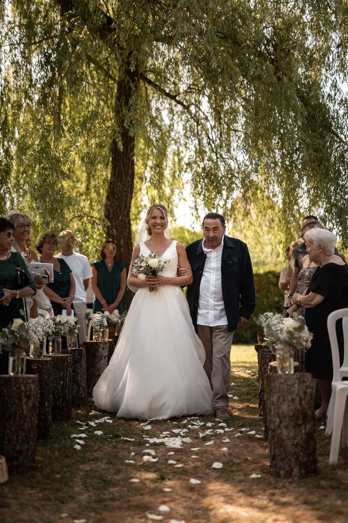 Entrée de la mariée au bras de son grand père pour une cérémonie laïque de mariage en extérieur sous le grand saule du Château d'Autigny-la-Tour.
