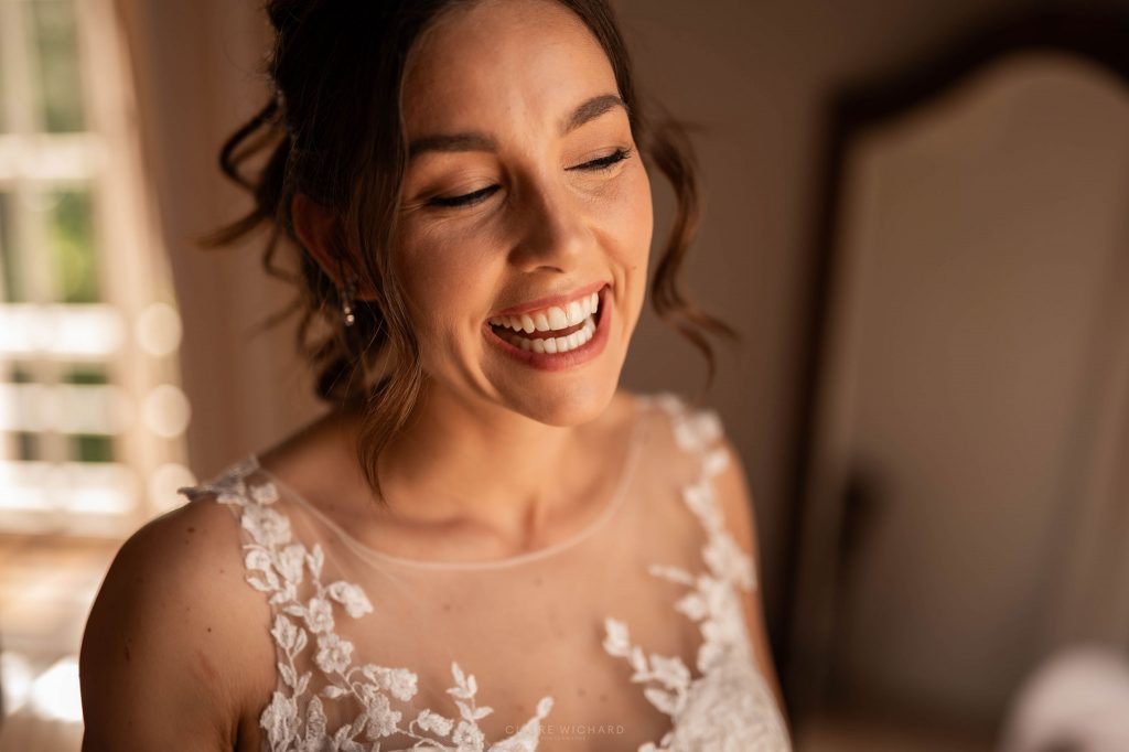 Portrait naturel et spontané de la mariée qui rit au château ferme d'aboncourt, maquillage et coiffure de mariage élégante, photographe de mariage Nancy