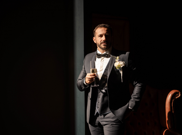 Reportage photo mariage Nancy : portrait d'u marié en costume noir tenant un verre.