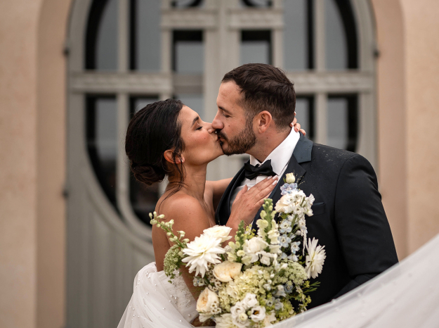 Photographe mariage Nancy : portrait de mariés s'embrassant devant une porte d'un château en Meurthe-et-Moselle.