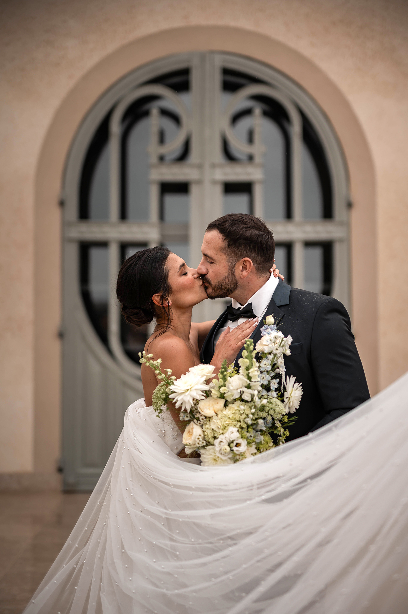Photographe mariage Nancy : portrait de mariés s'embrassant devant une porte d'un château en Meurthe-et-Moselle.