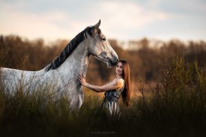 Femme aux cheveux longs et cheval gris dans les herbes dorées au Lac de Bouzey près de Nancy.