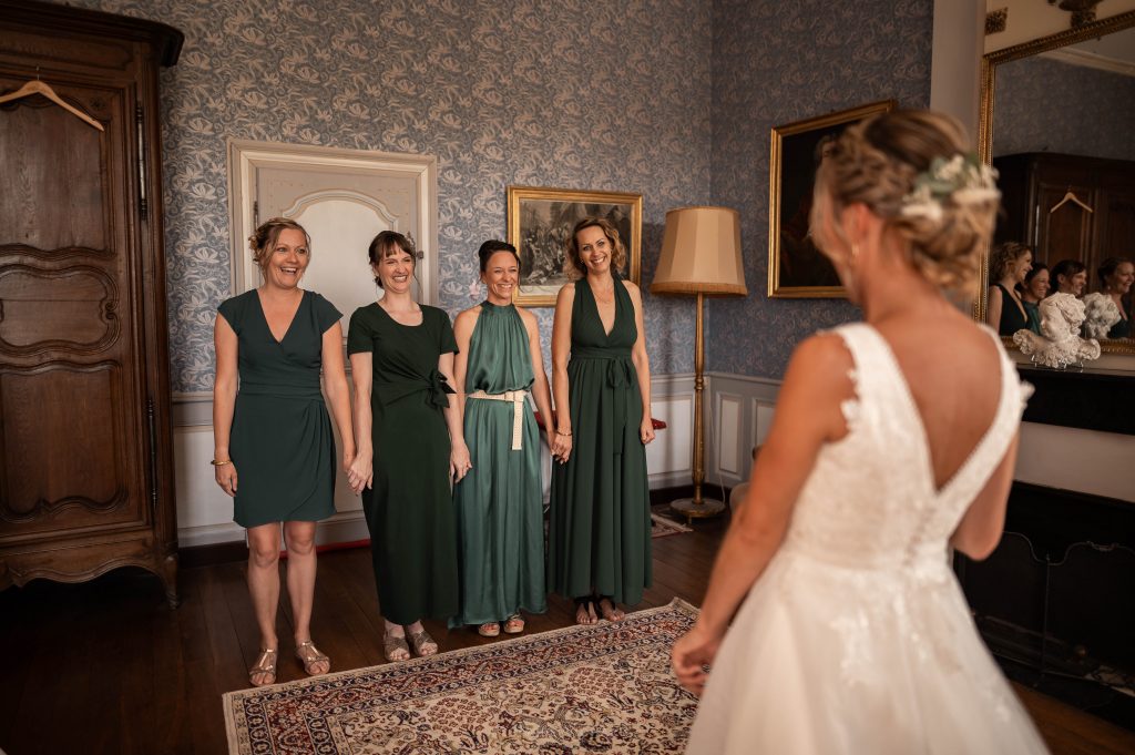 Les demoiselles d'honneur en robes vertes découvrent la mariée pour la première fois dans le salon du château