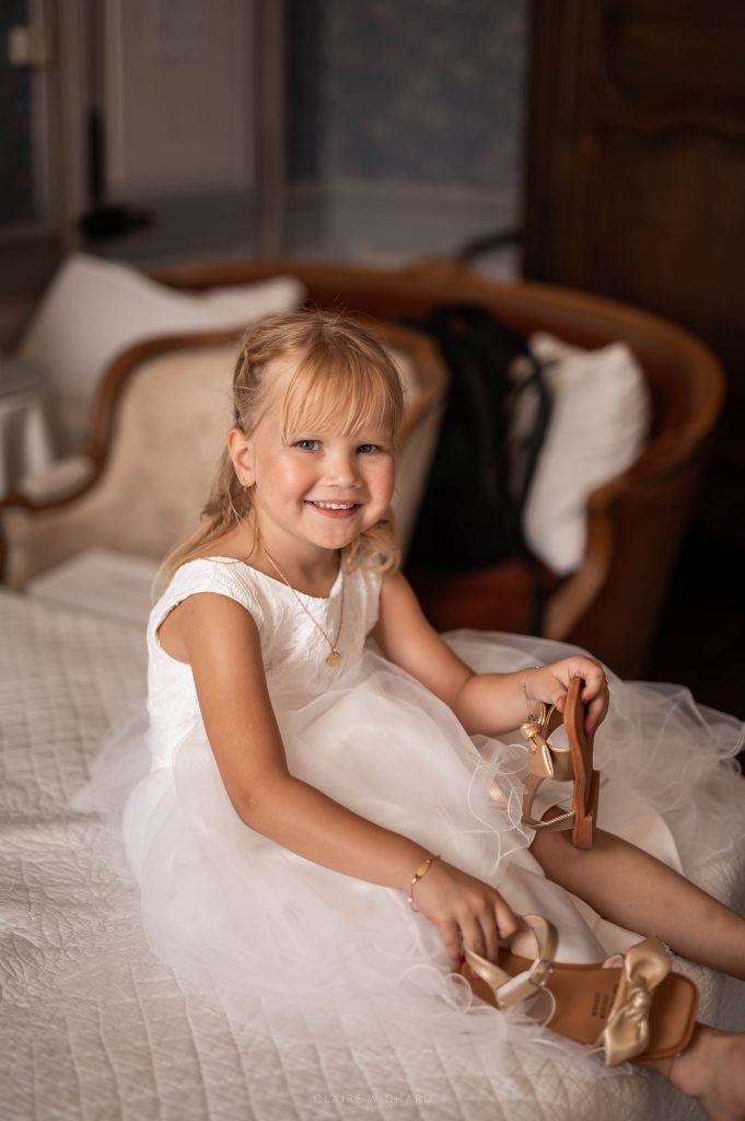 Portrait d'une petite fille d'honneur souriante sur un lit d'époque au Château d'Autigny-la-Tour.