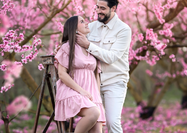 couple se regardant tendrement dans un verger de mirabelliers rose en fleurs proche de nancy