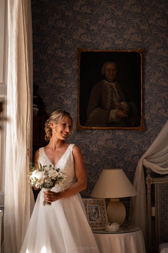 Mariée avec son bouquet de fleurs blanches, mise en valeur par une lumière naturelle douce près d'une fenêtre