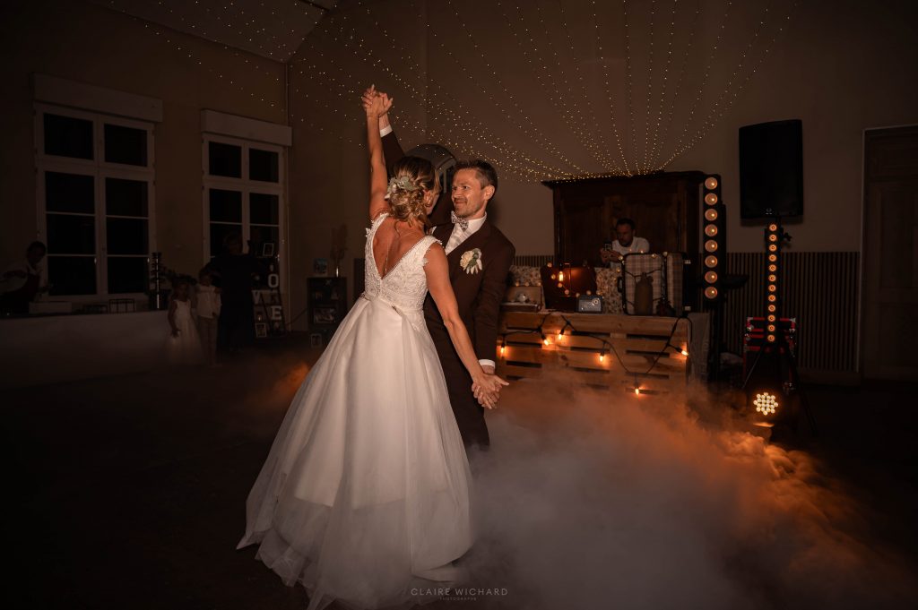 Image de Claire Wichard capturant la première danse des mariés au Château d'Autigny-la-Tour, dansant dans un nuage de fumée basse et sous un ciel de guirlandes, avec une belle complicité.