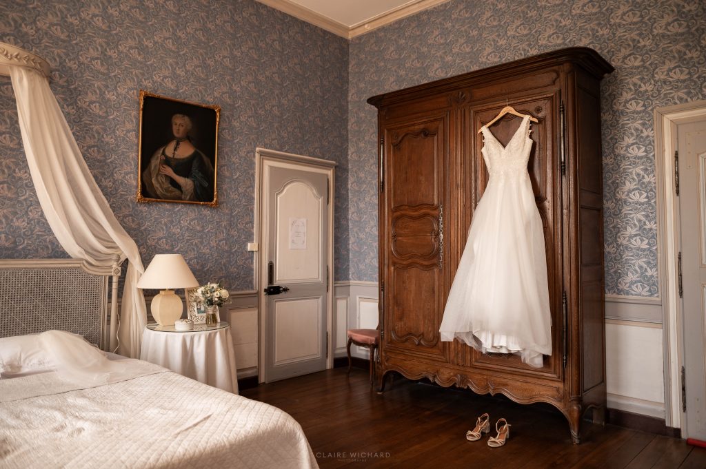 Robe de mariée suspendue sur une armoire ancienne dans une chambre au style Shabby Chic du château