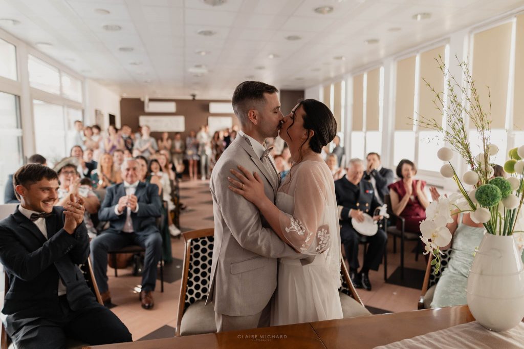 Échange du premier baiser des mariés devant l'autel de la mairie de Jarny sous le regard joyeux de leurs proches
