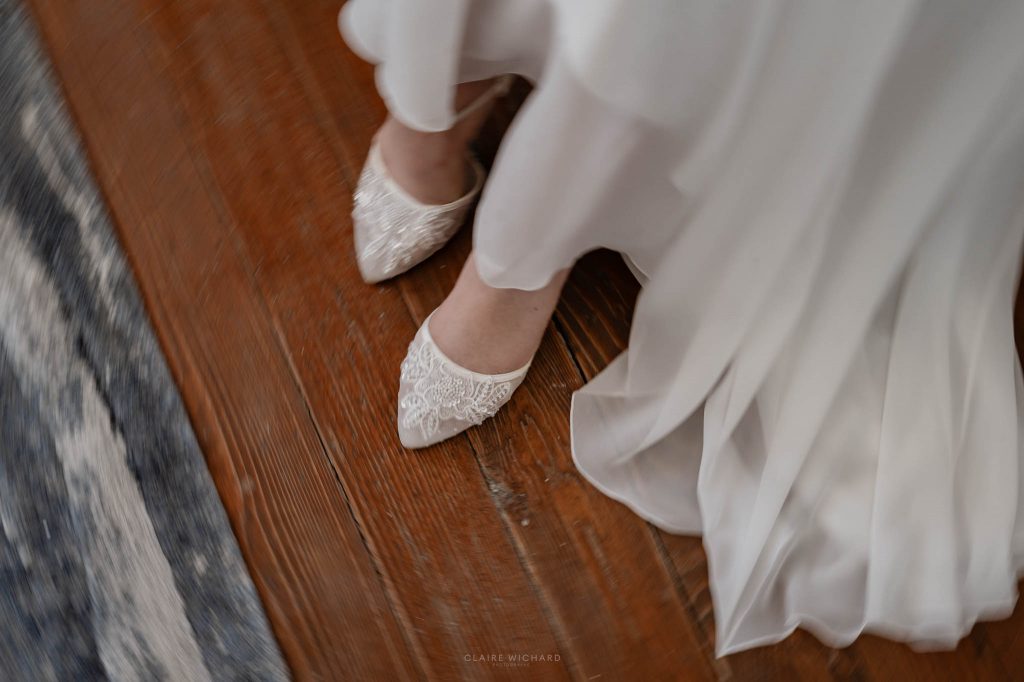 Gros plan sur les escarpins blancs en dentelle fine de la mariée sur un parquet ancien en bois à nancy