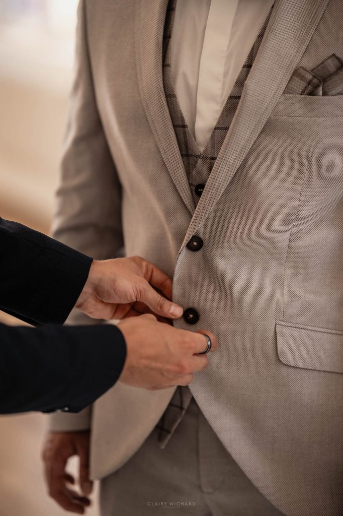 Détails du costume de marié beige avec gilet à carreaux et boutonnière ajustée par un proche en meurthe et moselle