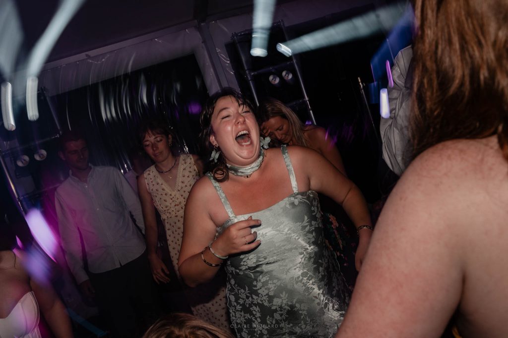 Une invitée en robe claire danse avec enthousiasme et chante sur la piste de danse pendant la soirée de mariage à Nancy