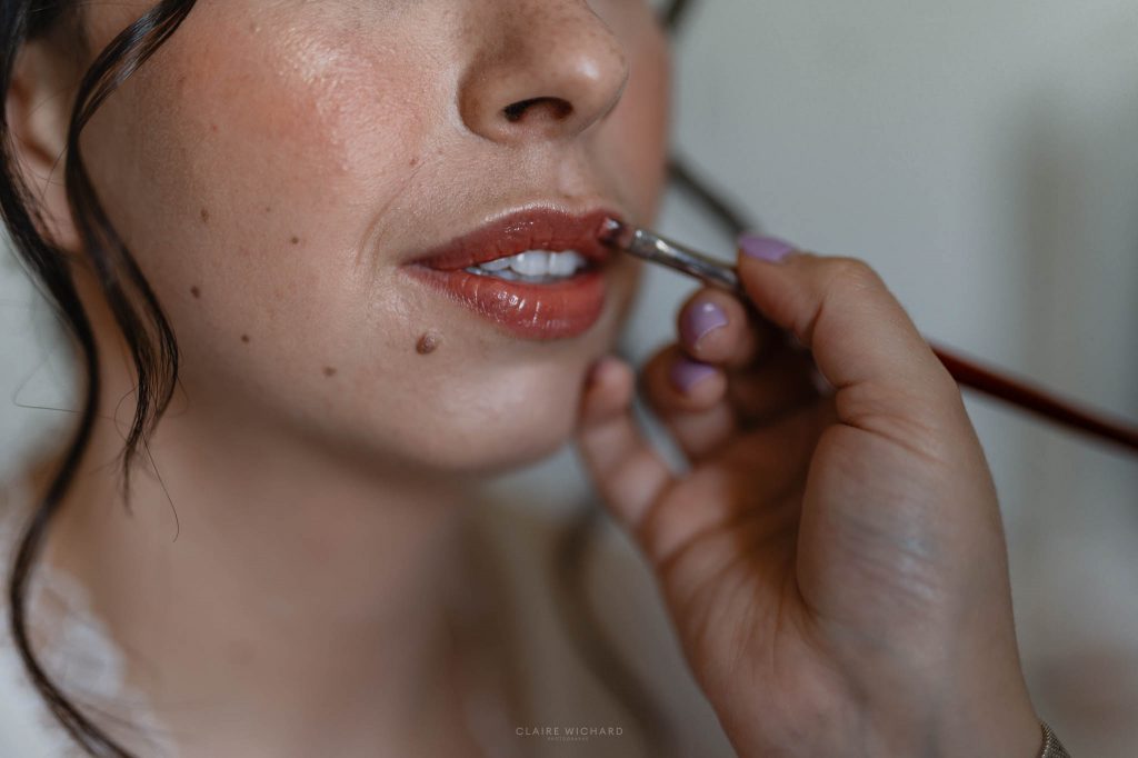 Gros plan sur la mise en beauté des lèvres de la mariée par une maquilleuse professionnelle lors des préparatifs proche de Nancy
