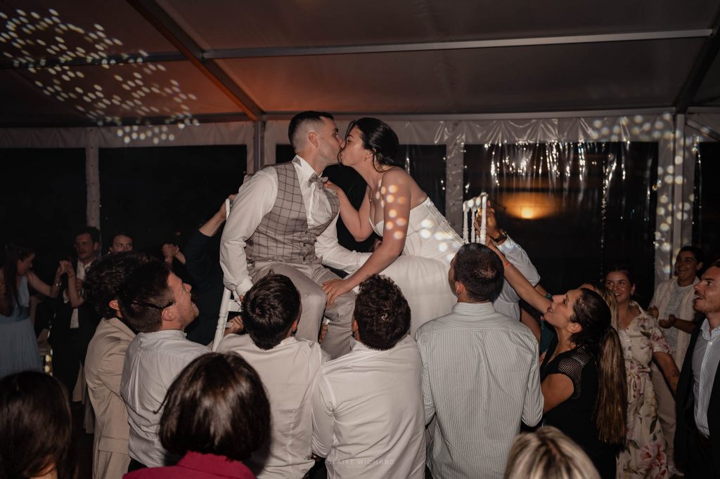 Les mariés sont soulevés sur des chaises par leurs invités et s'embrassent au milieu de la piste de danse en folie
