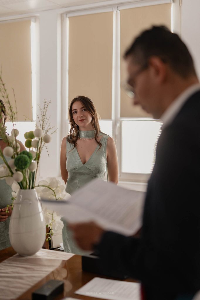Une témoin de mariage en robe verte élégante écoute attentivement le discours du maire de Jarny pendant la cérémonie