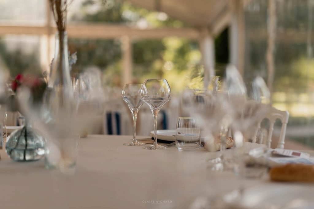 Gros plan artistique avec un effet de flou sur des verres à vin élégants disposés sur une table de mariage au chateau des aulnes