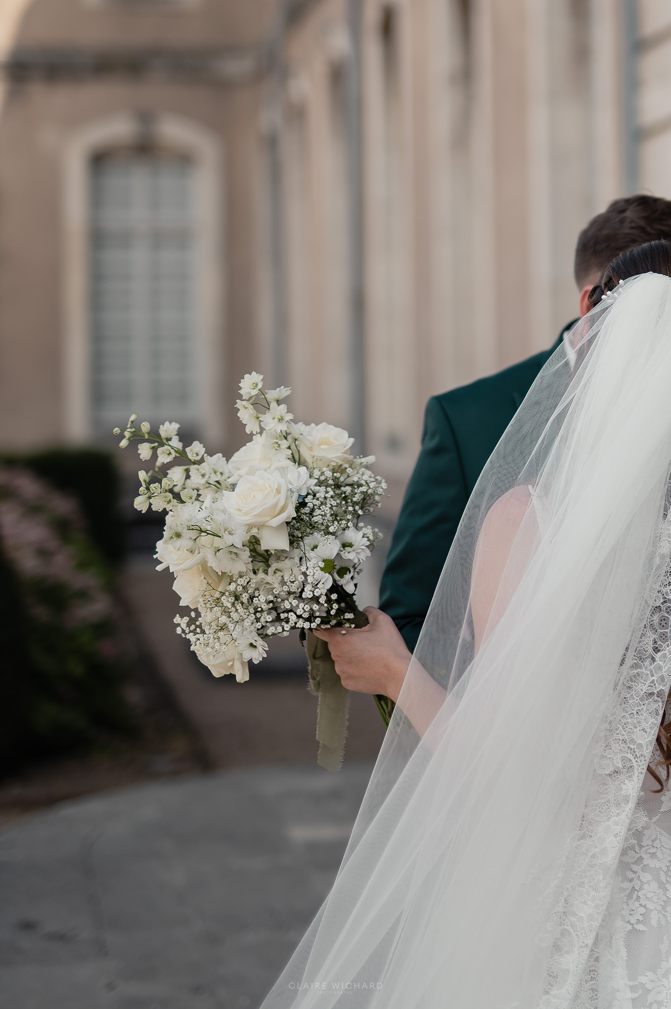 Mariée tenant un bouquet de roses blanches et gypsophile dans le cloître de l'Abbaye des Prémontrés, séance photo de mariage par Claire Wichard près de Nancy