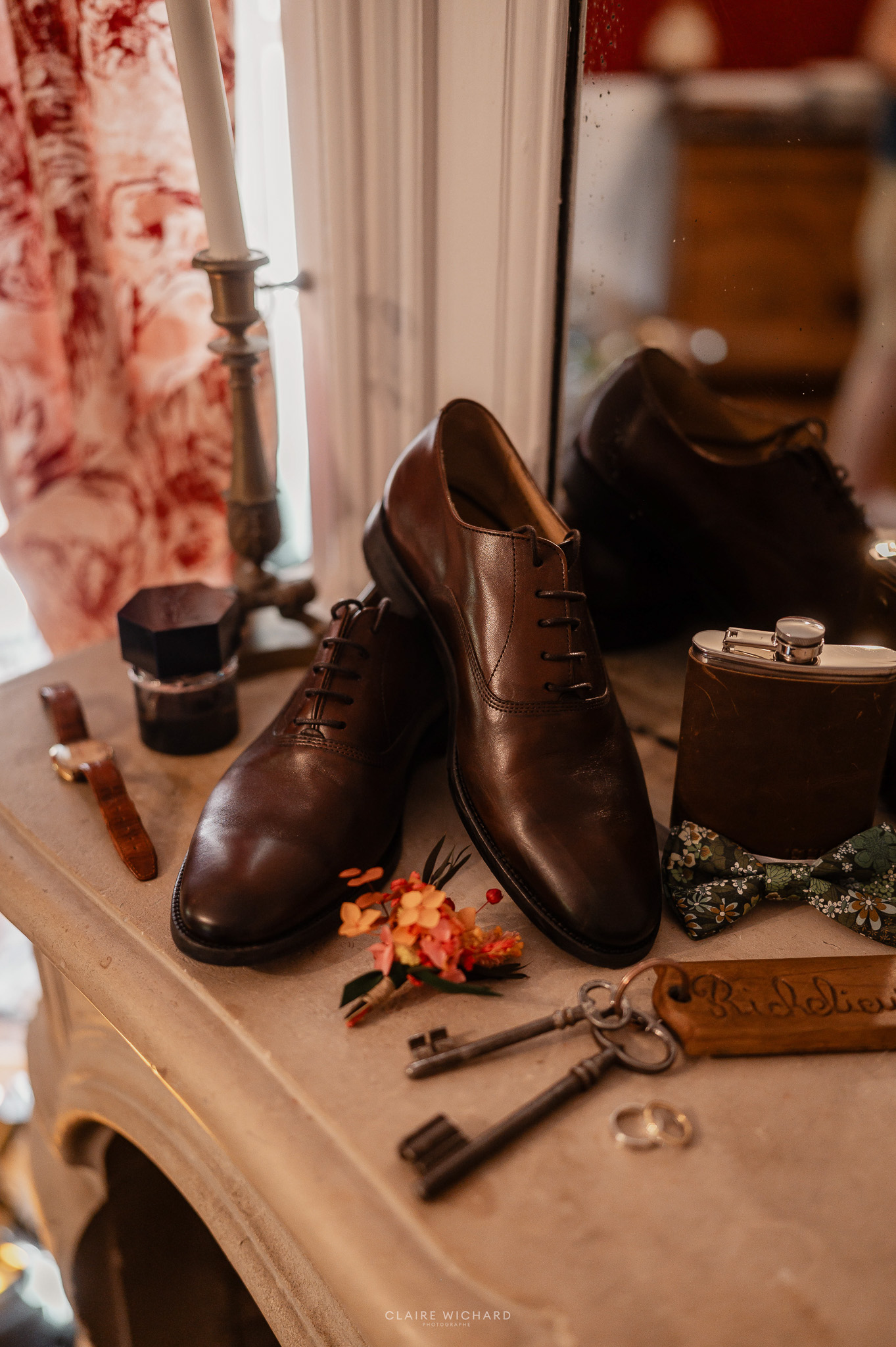 Détails des accessoires du marié comprenant chaussures en cuir, nœud papillon et clés anciennes au Château de Hattonchâtel par Claire Wichard.
