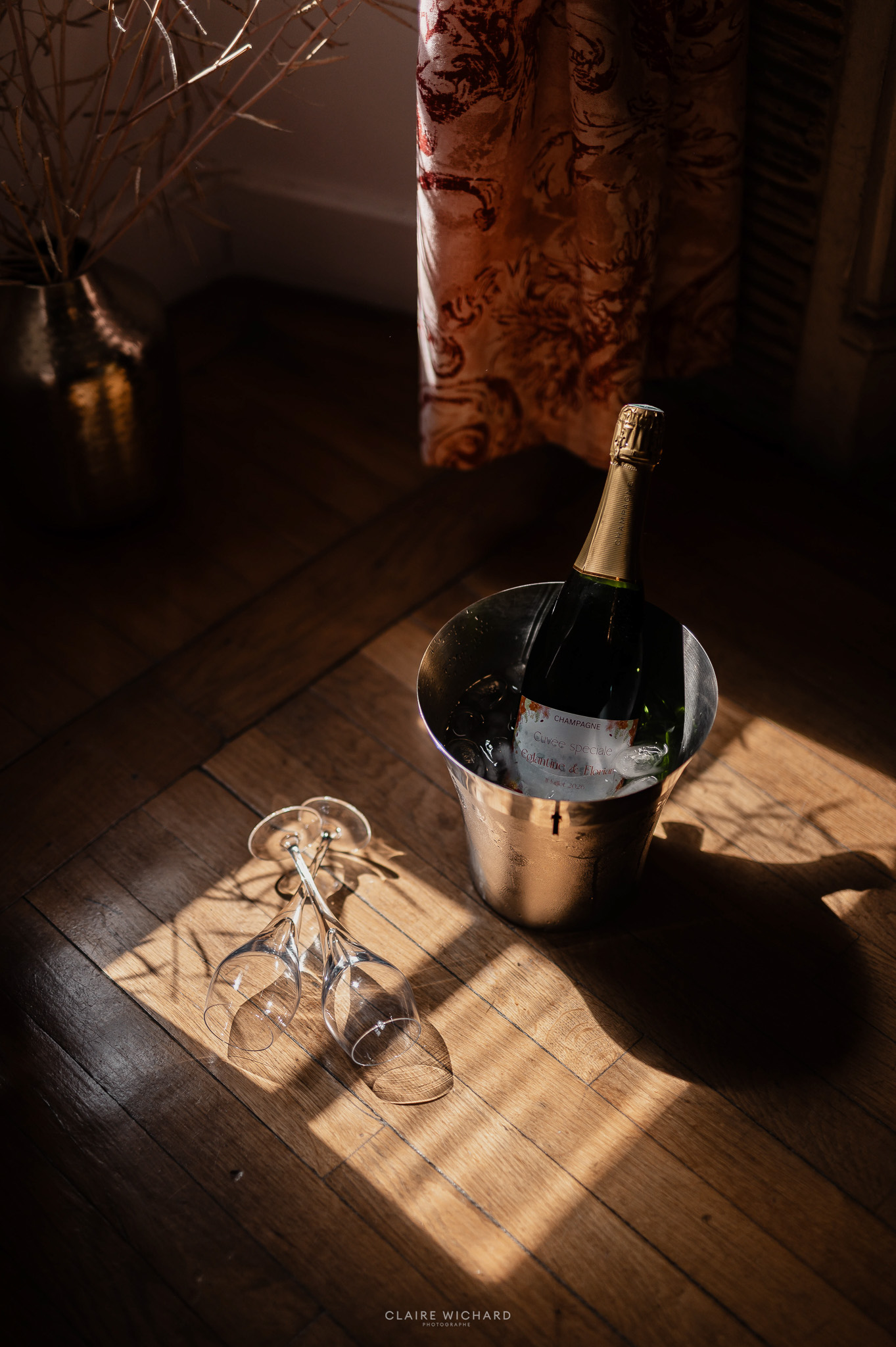 Bouteille de champagne rafraîchie et flûtes posées sur parquet lors d'un mariage au Château de Hattonchâtel, photographie Claire Wichard Photographe en Lorraine.