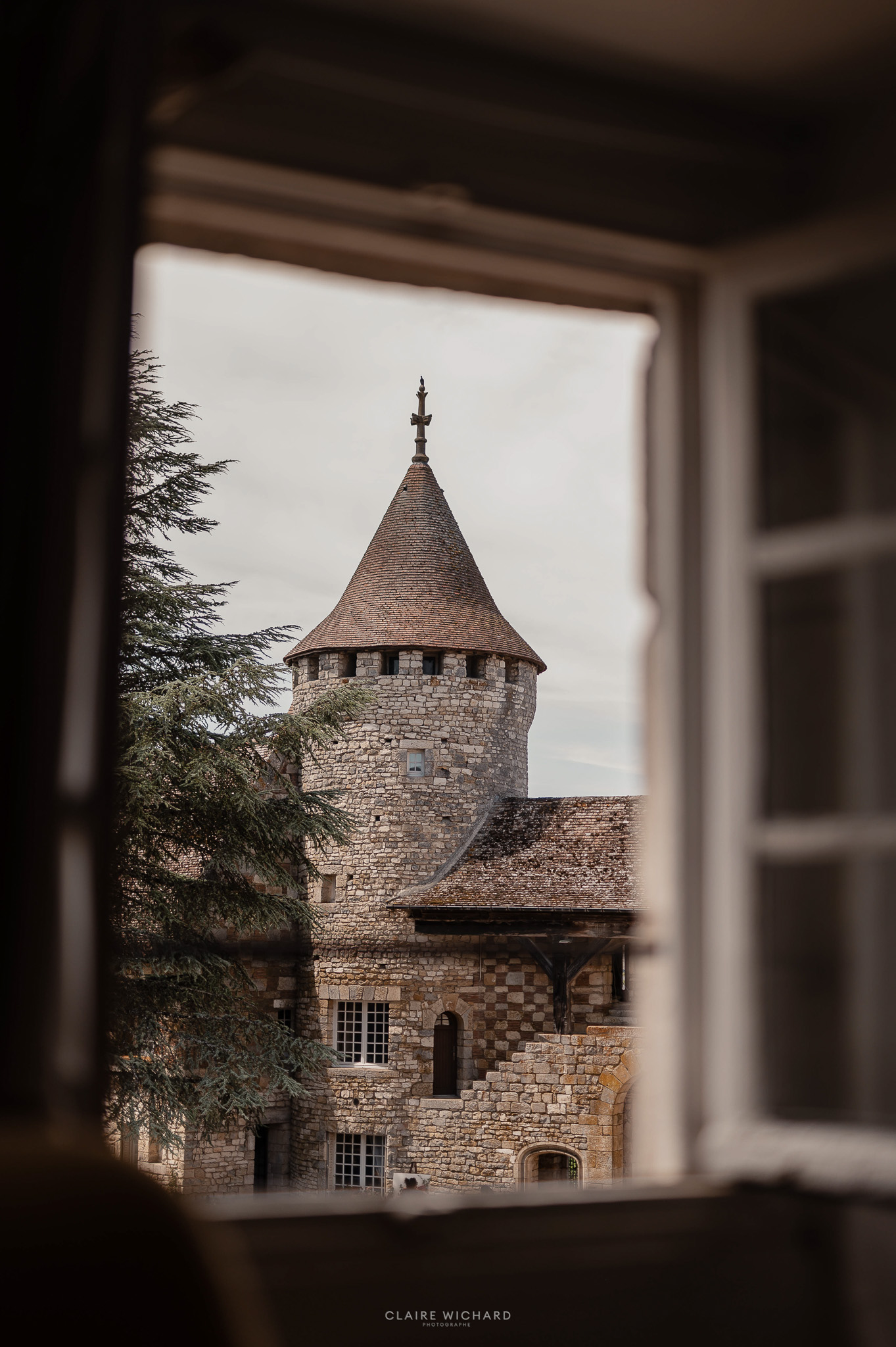 Vue sur la tour en pierre du Château de Hattonchâtel à travers une fenêtre, prise lors d'un reportage mariage par Claire Wichard, photographe proche de Nancy.