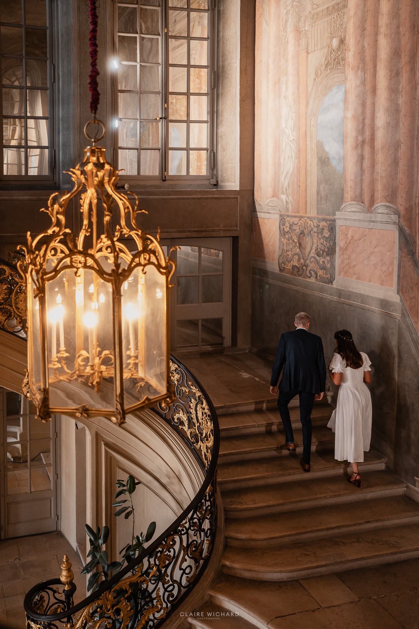 Photographie d'architecture en noir et blanc de l'escalier d'honneur de l'hôtel de ville de Nancy, Place Stanislas, avec des mariés qui montent.