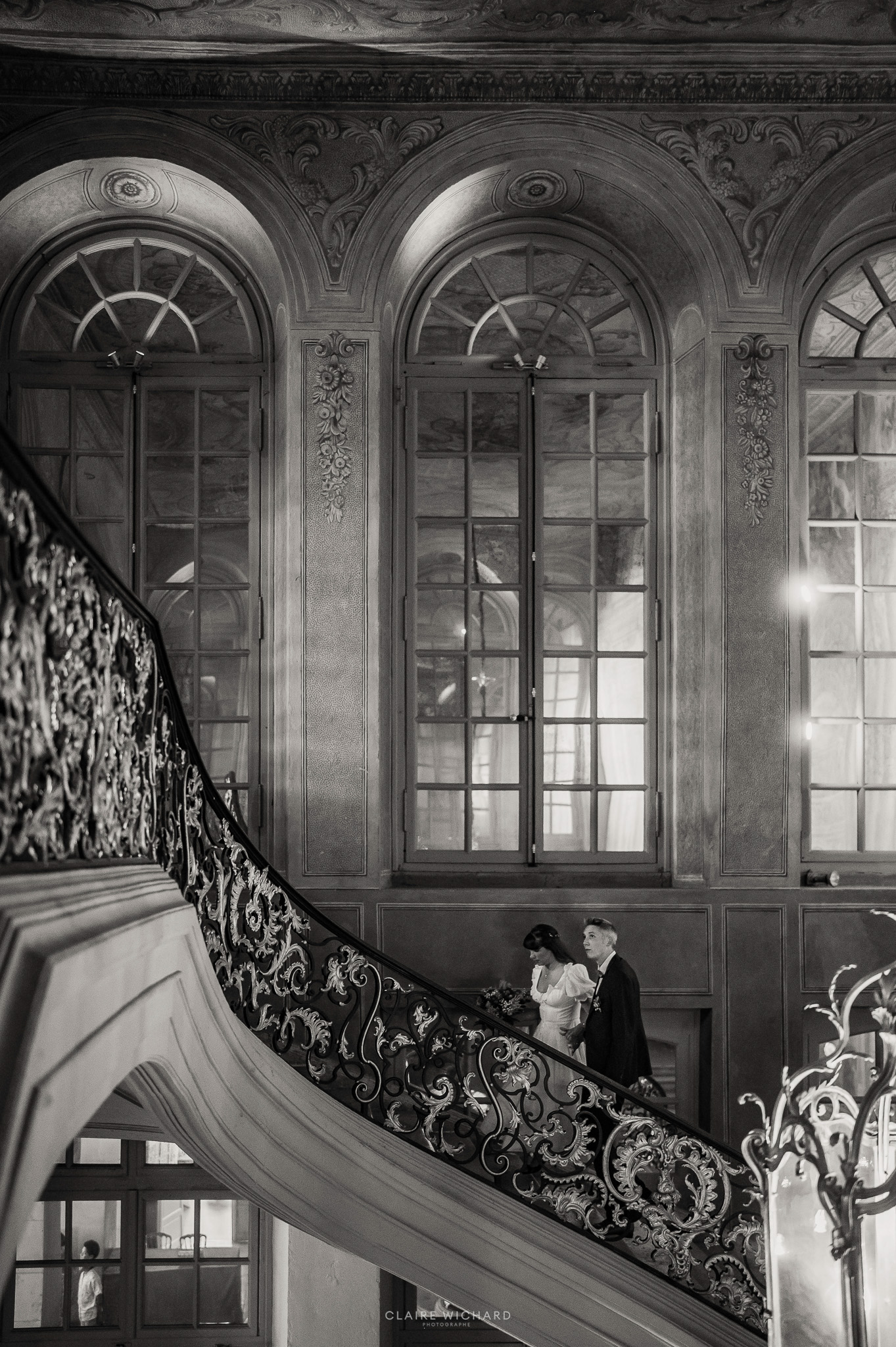 Intérieur somptueux du salon d'honneur de la mairie de Nancy avec un grand lustre en cristal doré, un couple de mariés s'éloignant sur les marches.