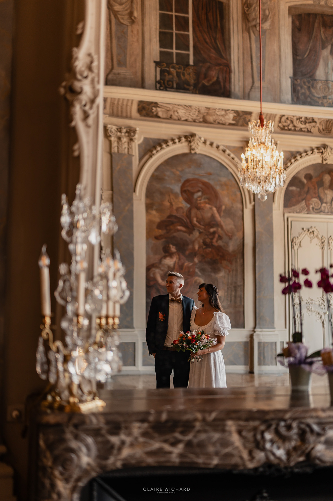 Reflet créatif d'un couple de mariés s'embrassant dans un grand miroir doré dans un salon d'honneur de la mairie de Nancy.