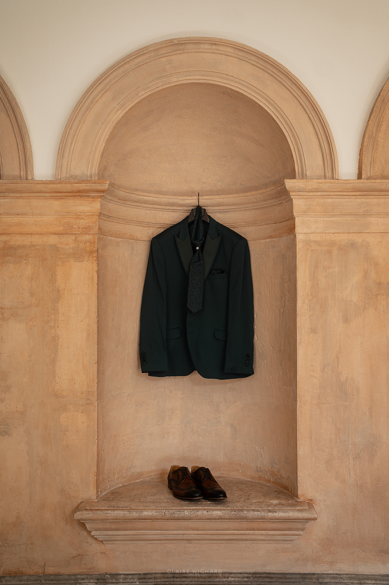 Costume de marié vert vert sapin et chaussures suspendus dans une niche architecturale de l'Abbaye des Prémontrés, préparatifs de mariage à Nancy par Claire Wichard