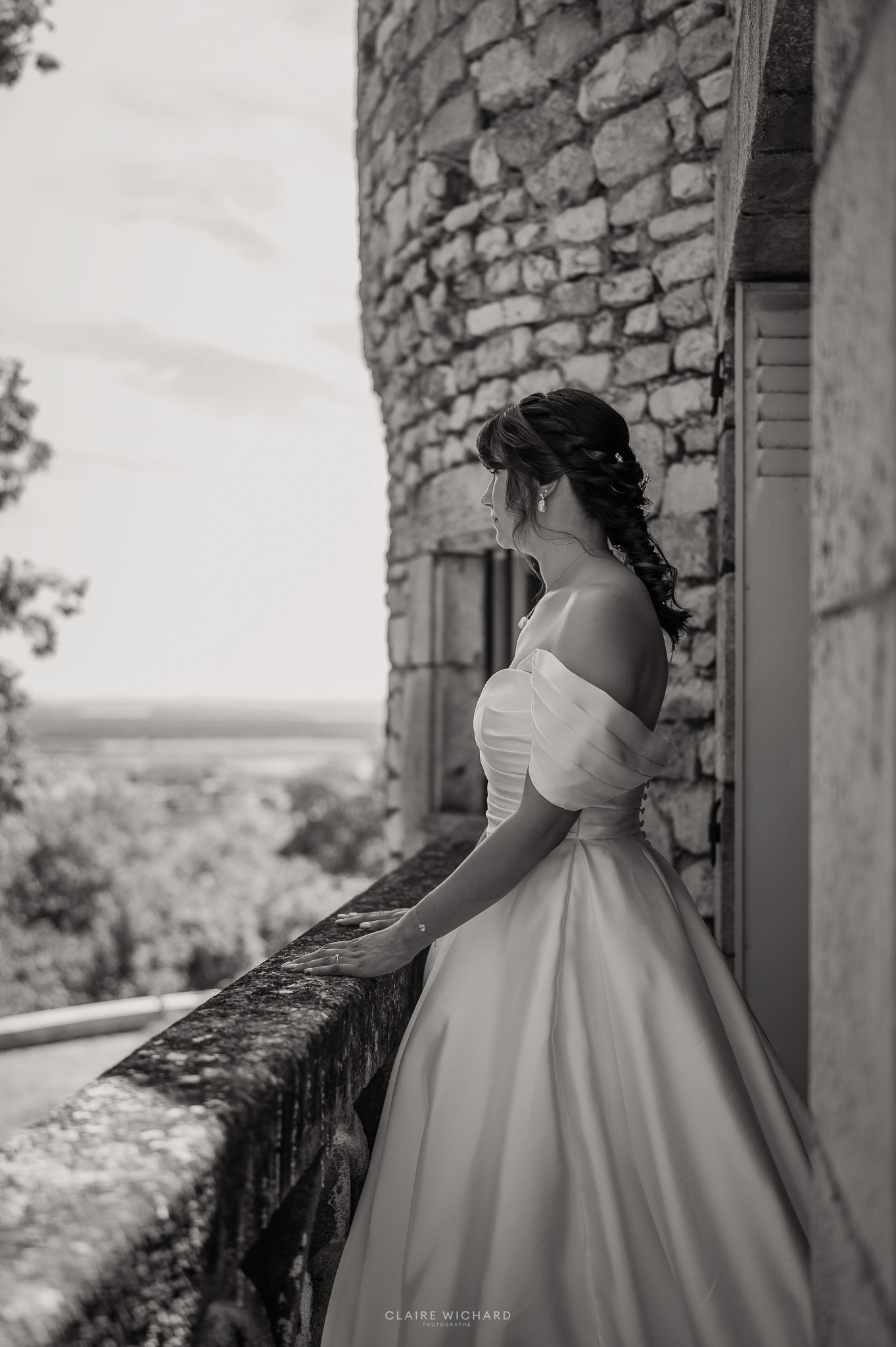 Portrait de mariée en noir et blanc au balcon du Château de Hattonchâtel avec vue sur la région, réalisé par Claire Wichard, photographe de mariage en Lorraine.