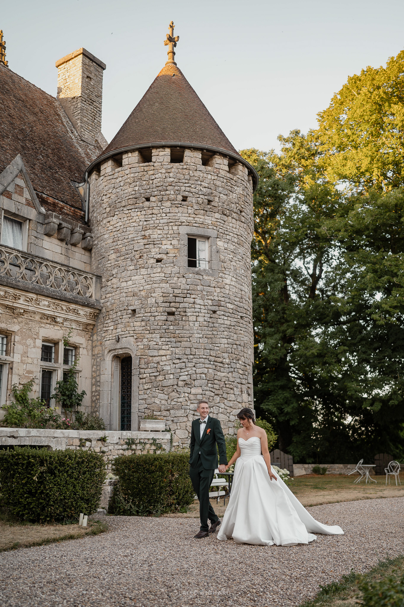 Photographie de mariage au Château de Hattonchâtel par Claire Wichard, photographe de mariage à Nancy et en Lorraine. Mariés marchant devant la tour médiévale.
